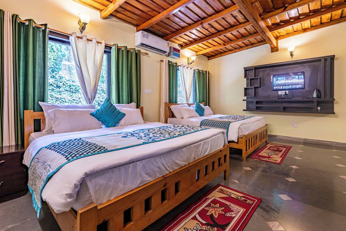 A hotel room with two wooden beds, green curtains, a flat-screen TV, and a ceiling fan.