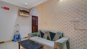 A room with a sofa, a small table, a water dispenser, and a 'No Alcohol' sign. - iROOMZ Hotel Silver Moon (Hyderabad)