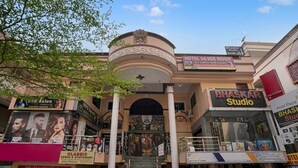 A multi-story building with a central staircase, signs for Hotel Silver Moon and Bhaskar Studio, and various storefronts including a salon and a printing service. - iROOMZ Hotel Silver Moon (Hyderabad)