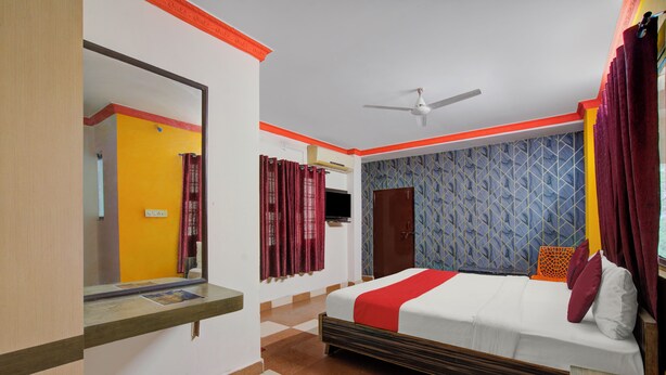 A hotel room with a bed, a ceiling fan, a TV, and a window with curtains. - iROOMZ Hotel Silver Moon (Hyderabad)