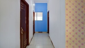 A narrow hallway with a blue door at the end, leading to a room with a window. - iROOMZ Hotel Silver Moon (Hyderabad)
