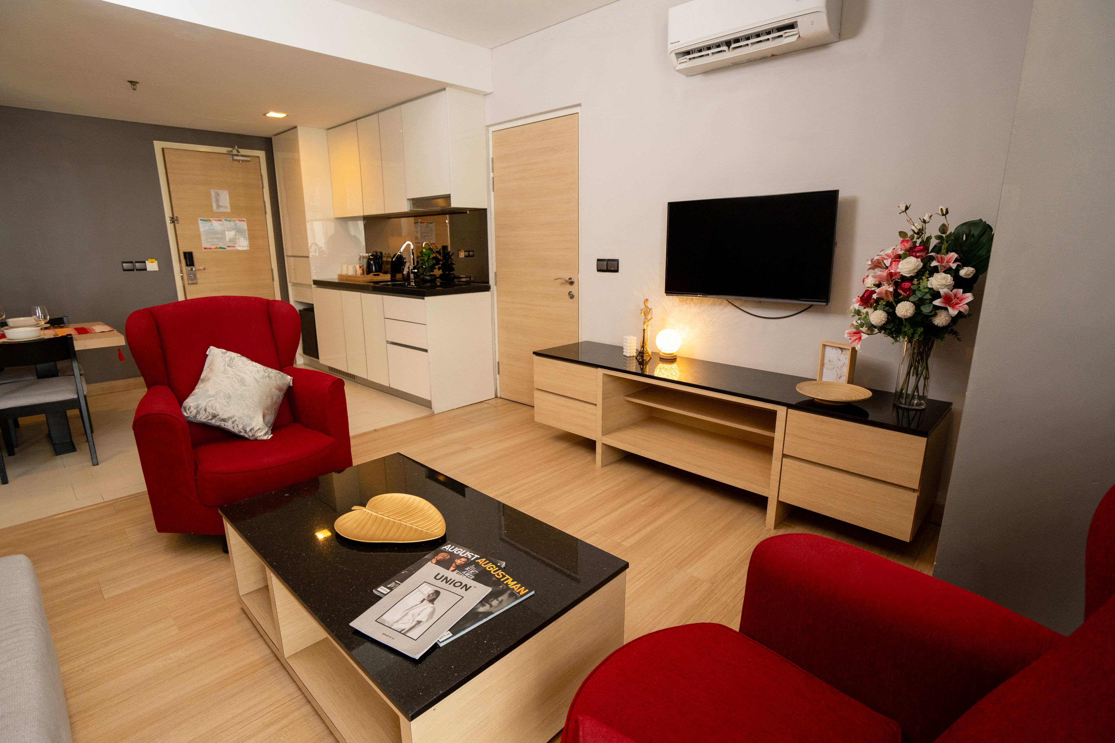 A modern living room with a red armchair, a black coffee table, and a TV mounted on the wall.