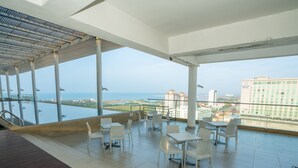 Een ruim balkon met uitzicht op zee en gebouwen.