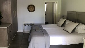 A bedroom with two beds, a bedside table, a wardrobe, and a small seating area. - Luxury 5 roomed Villa with A/C, swimming pool etc. in Victoria Falls, Zimbabwe (Victoria Falls)