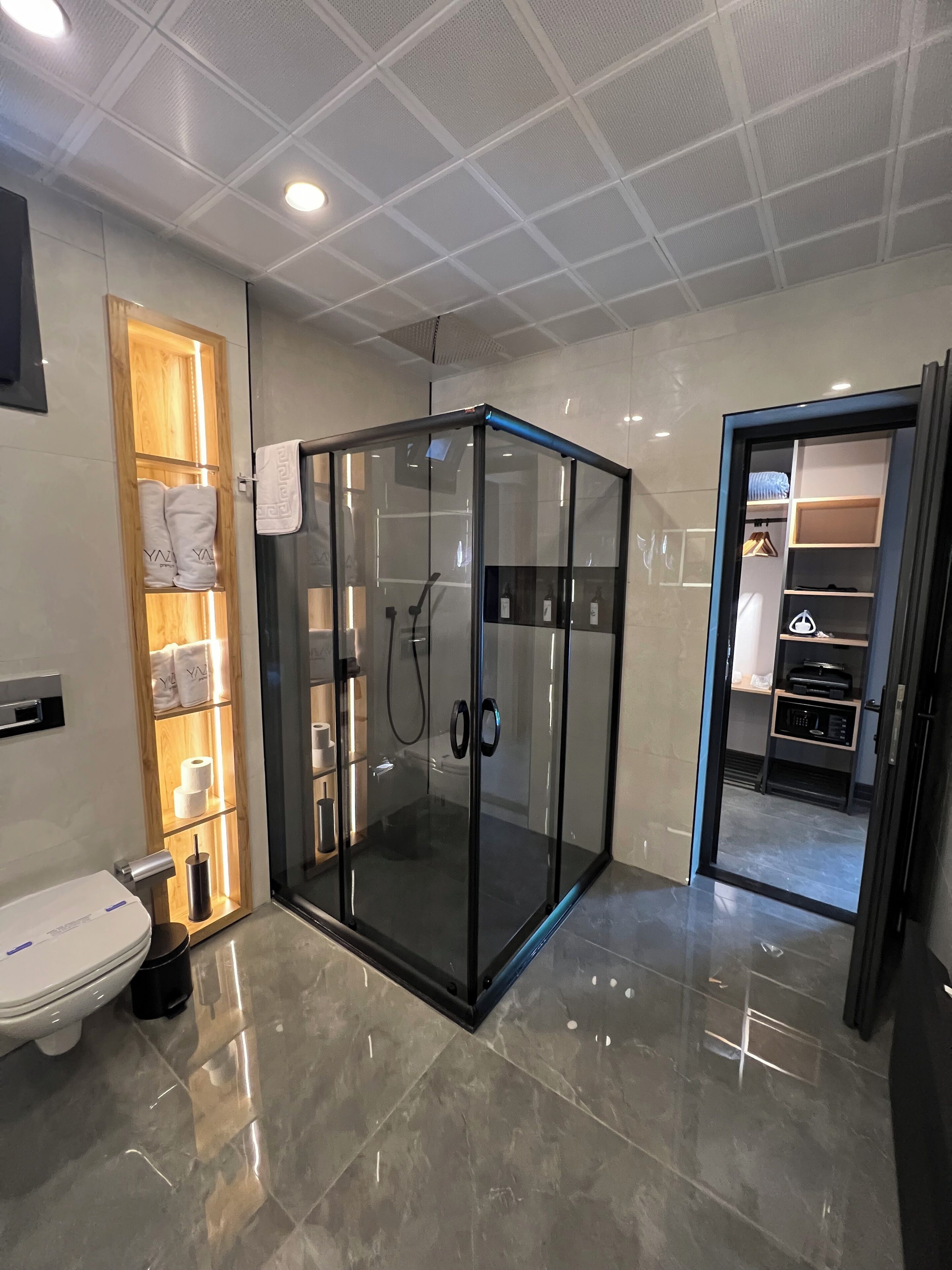 Un baño moderno con ducha envuelta en vidrio, un inodoro y un tocador con espejo.