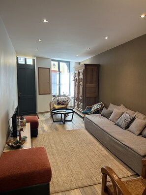 A living room with a sofa, a coffee table, a chair, and a TV.