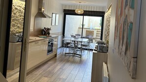 A modern kitchen with a central island, wooden flooring, and a dining area with a table and chairs. - By the ramparts, house with pool & stunning view, guesthouse La Trivala (Carcassonne)