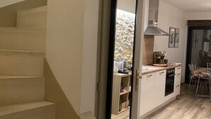 A modern kitchen with wooden flooring, a built-in oven, and a dining area with a table and chairs. - By the ramparts, house with pool & stunning view, guesthouse La Trivala (Carcassonne)