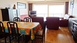 A dining area with a colorful tablecloth, a television, and a sofa. - Apartment in Nieuwpoort near the Beach (Nieuwpoort)