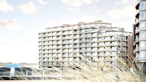 A multi-story residential building with balconies, a clear sky, and a fence in the foreground. - Apartment in Nieuwpoort near the Beach (Nieuwpoort)