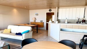 Una sala moderna con sofá, mesa de comedor y zona de cocina con armarios y una bicicleta.