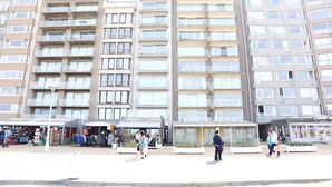 Un edificio residencial de varios pisos, con balcones y un área comercial en la planta baja con tiendas.
