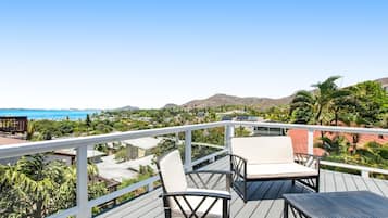 Enjoy breathtaking views of the coastline from this balcony, featuring a comfortable seating area with two chairs and a table.