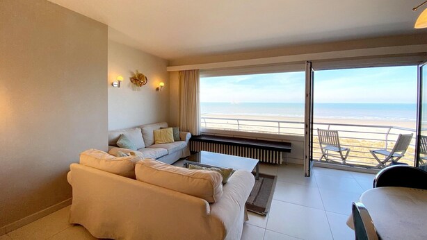 Une chambre d’hôtel moderne dotée d’un grand balcon, d’un canapé, d’une table basse et offrant une vue sur la plage.