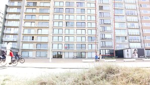 Un immeuble résidentiel à plusieurs étages, doté de balcons, d’une entrée sécurisée et d’un vélo garé devant.