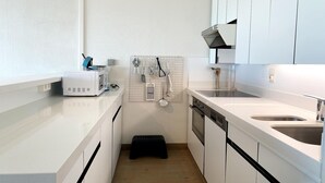 A modern kitchen with white cabinets, a built-in oven, a double sink, and a countertop microwave. - Apartment in Nieuwpoort by the Beach (Nieuwpoort)