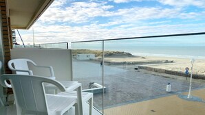 A balcony with white plastic chairs and a table, overlooking a beach with a sandy shore and waves. - Apartment in Nieuwpoort by the Beach (Nieuwpoort)