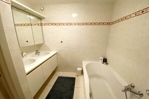 A bathroom with two sinks, a mirror, a toilet, and a bathtub. - Apartment in Nieuwpoort near the Beach (Nieuwpoort)