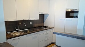 Een moderne keuken met witte kastjes, een roestvrijstalen spoelbak en een inbouwoven.