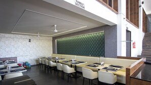 A family section of a restaurant with booths and tables, a green cushioned wall, and a staircase. - Monarch Express (Rajgurunagar)