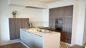 Una cocina moderna con una isla central, electrodomésticos de acero inoxidable y muebles de madera.