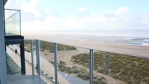 Un edificio moderno con balcón de vidrio con vistas a una playa y un paisaje desértico.