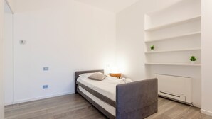 Ein modernes Schlafzimmer mit Bett, Nachttisch und Heizkörper.