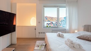 Ein Hotelzimmer mit Bett, Fernseher, Fenster mit Blick auf Gebäude und Nachttisch mit Handtüchern.