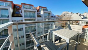 Un moderno edificio de apartamentos con varios balcones, ventanas amplias y cielo despejado.