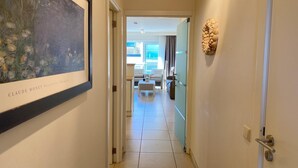 Un pasillo con un cuadro enmarcado, un espacio moderno de sala con un sofá y una mesa de centro, y un adorno en la pared.