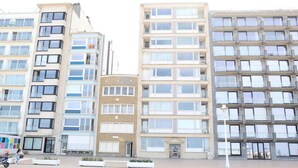 Een rij middelgrote woongebouwen met meerdere balkons, grote ramen en een centrale ingang.