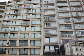 A multi-story building with balconies, large windows, and a sign indicating a restaurant. - Picturesque apartment in Nieuwpoort (Nieuwpoort)