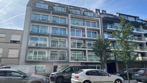 A multi-story residential building with balconies, a parking area, and a tree in front. - Apartment in Nieuwpoort near Sandy Beaches (Nieuwpoort)