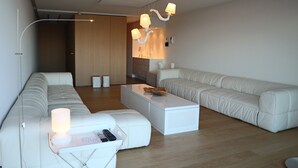 A modern living room with a white sofa set, a white coffee table, and a unique hanging light fixture. - Romantic Coastal Escape (Nieuwpoort)