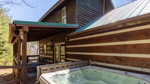 A wooden cabin with a hot tub outside, a covered patio, and a dining area. - Mountain Vintage (Sevierville)