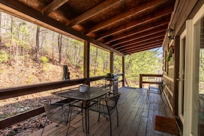 Enjoy al fresco dining on this outdoor deck with a forest view, complete with a grill and comfortable seating.