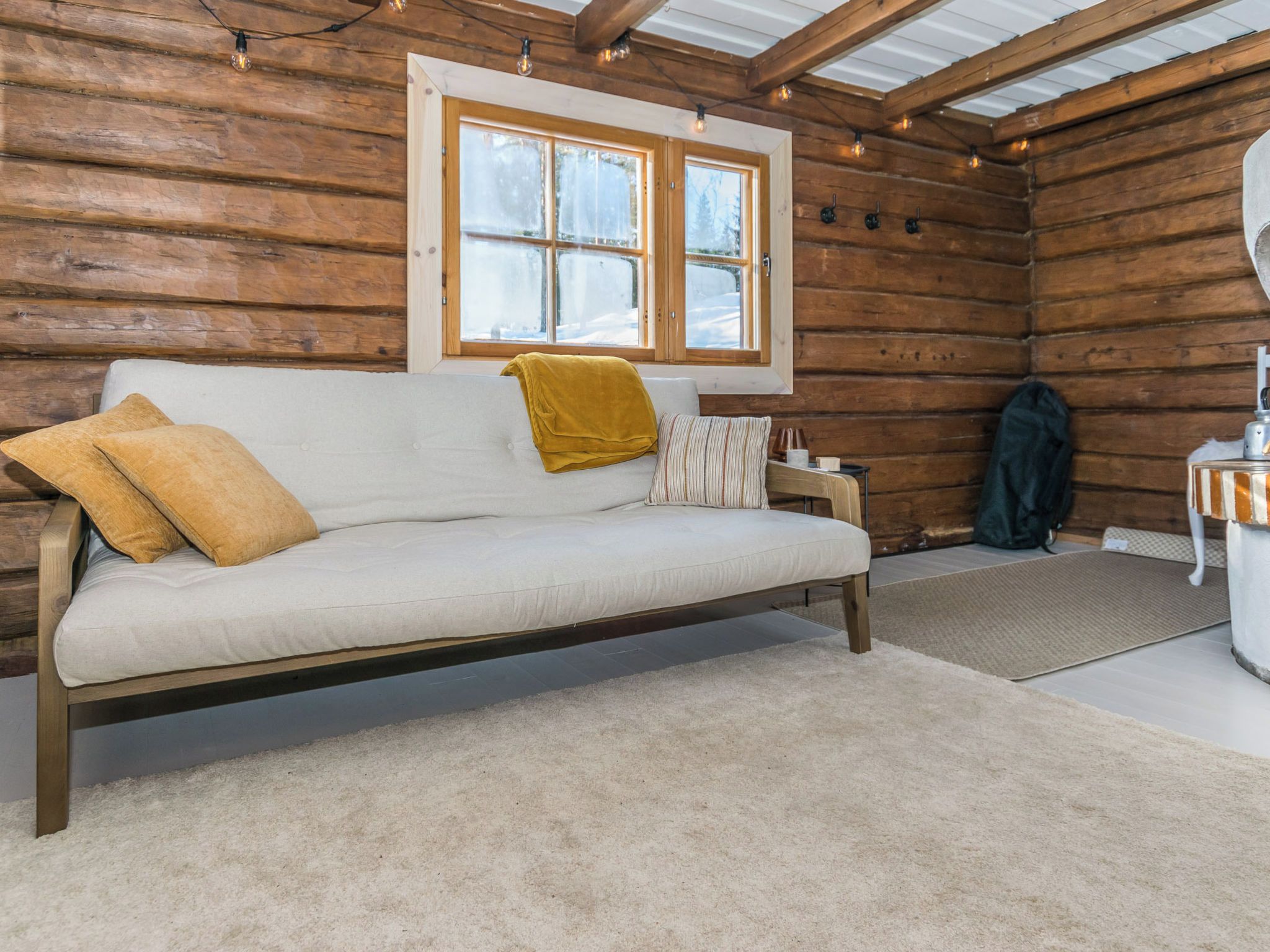 L'intérieur d'une cabane en rondins, avec un canapé, une fenêtre et une petite table.