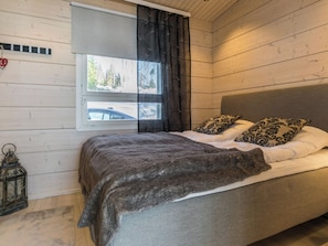 Un dormitorio con cama, una ventana con cortinas, un farol y un reloj de pared.