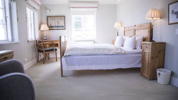 A bedroom with a bed, bedside tables, a chair, a desk, and a window with curtains.