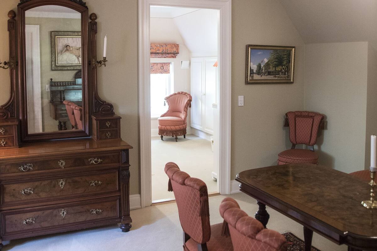 Ein Esszimmer mit Holztisch und -stühlen, einem großen Spiegel und einem gemusterten Teppich.