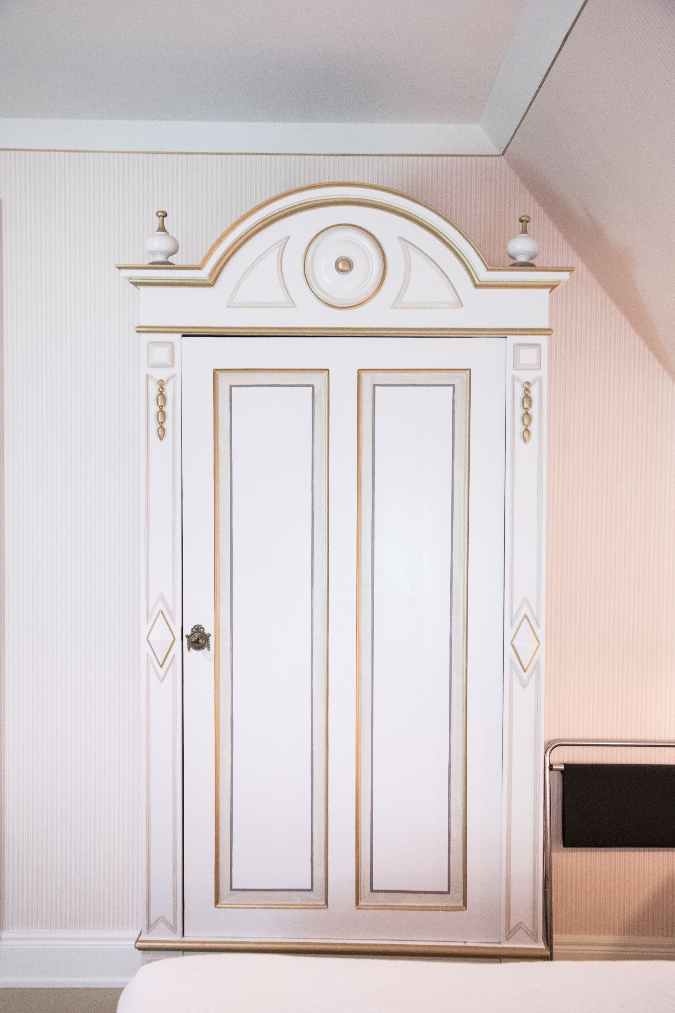 Un armario blanco con detalles dorados y elementos decorativos.