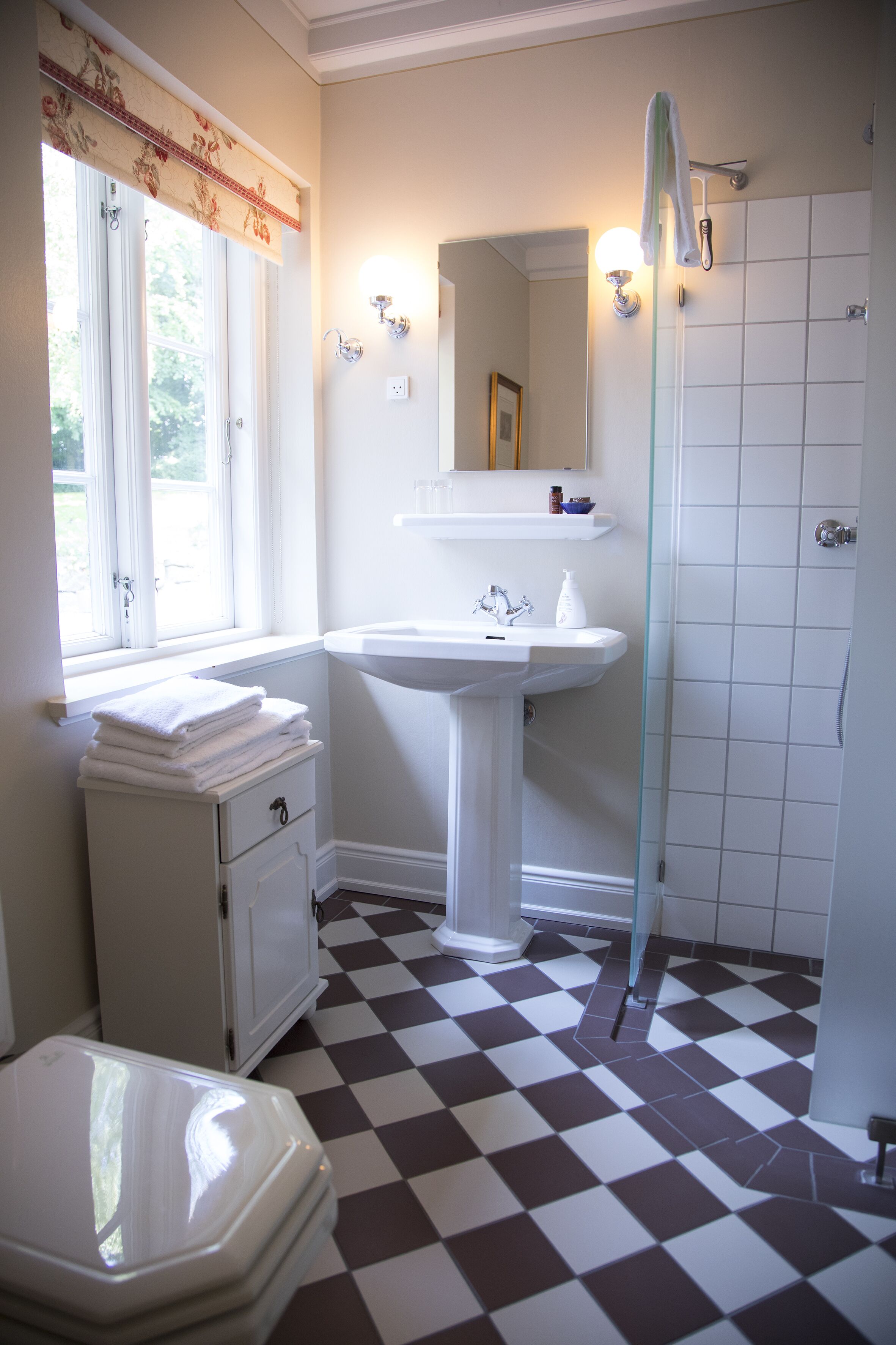 Ein Badezimmer mit Schachbrettboden, einem Waschbecken, einer Toilette und einer Dusche.