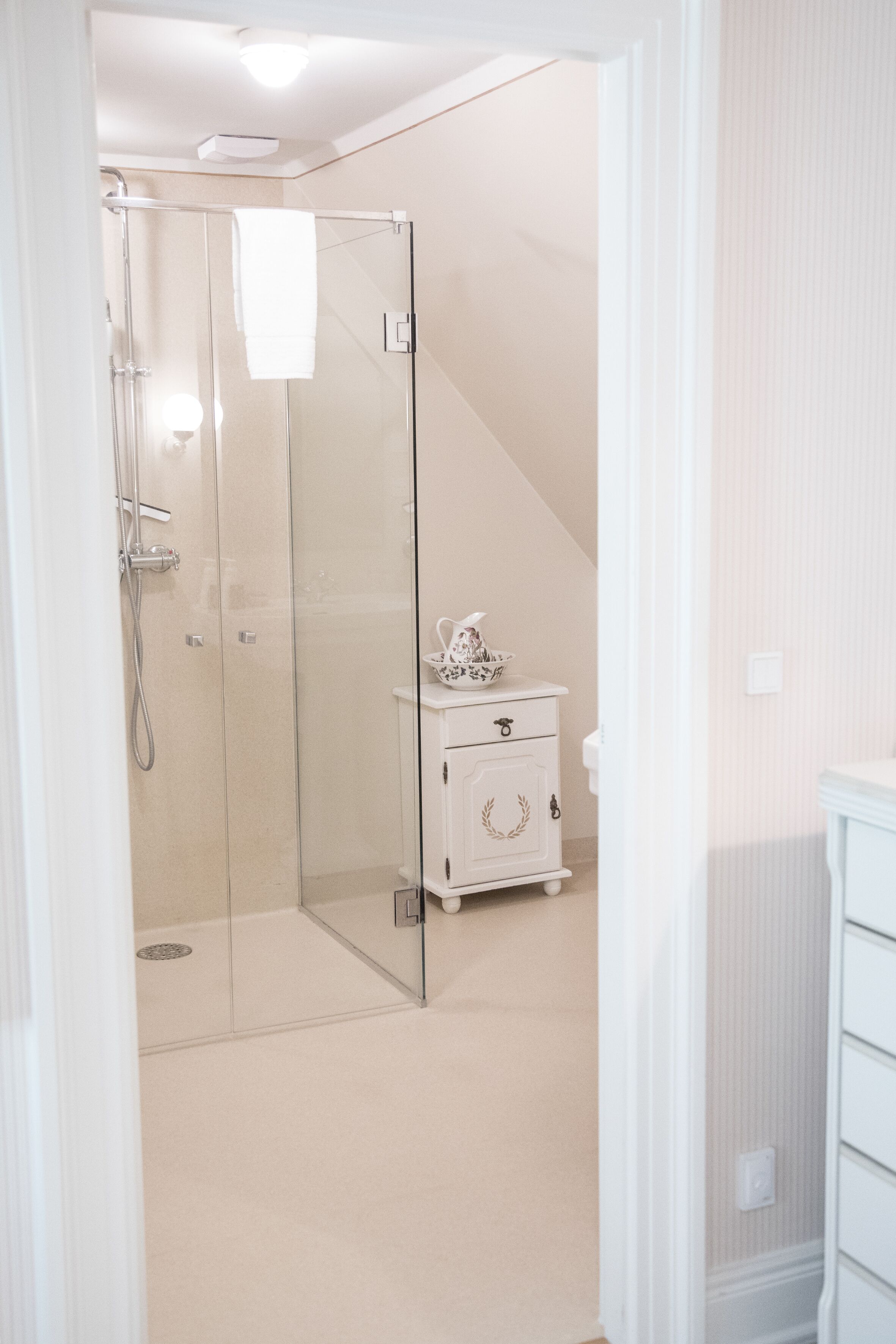 A modern bathroom with a glass shower enclosure, a white vanity with a decorative bowl, and a light-colored floor.