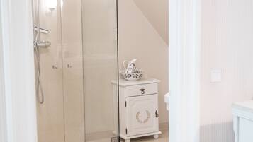Een moderne badkamer met een douchecabine van glas, een witte wastafel met decoratieve kom en een vloer in een lichte kleur.