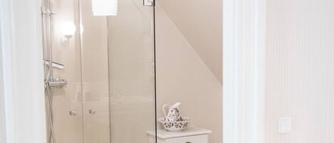 A modern bathroom with a glass shower enclosure, a white vanity with a decorative bowl, and a light-colored floor.