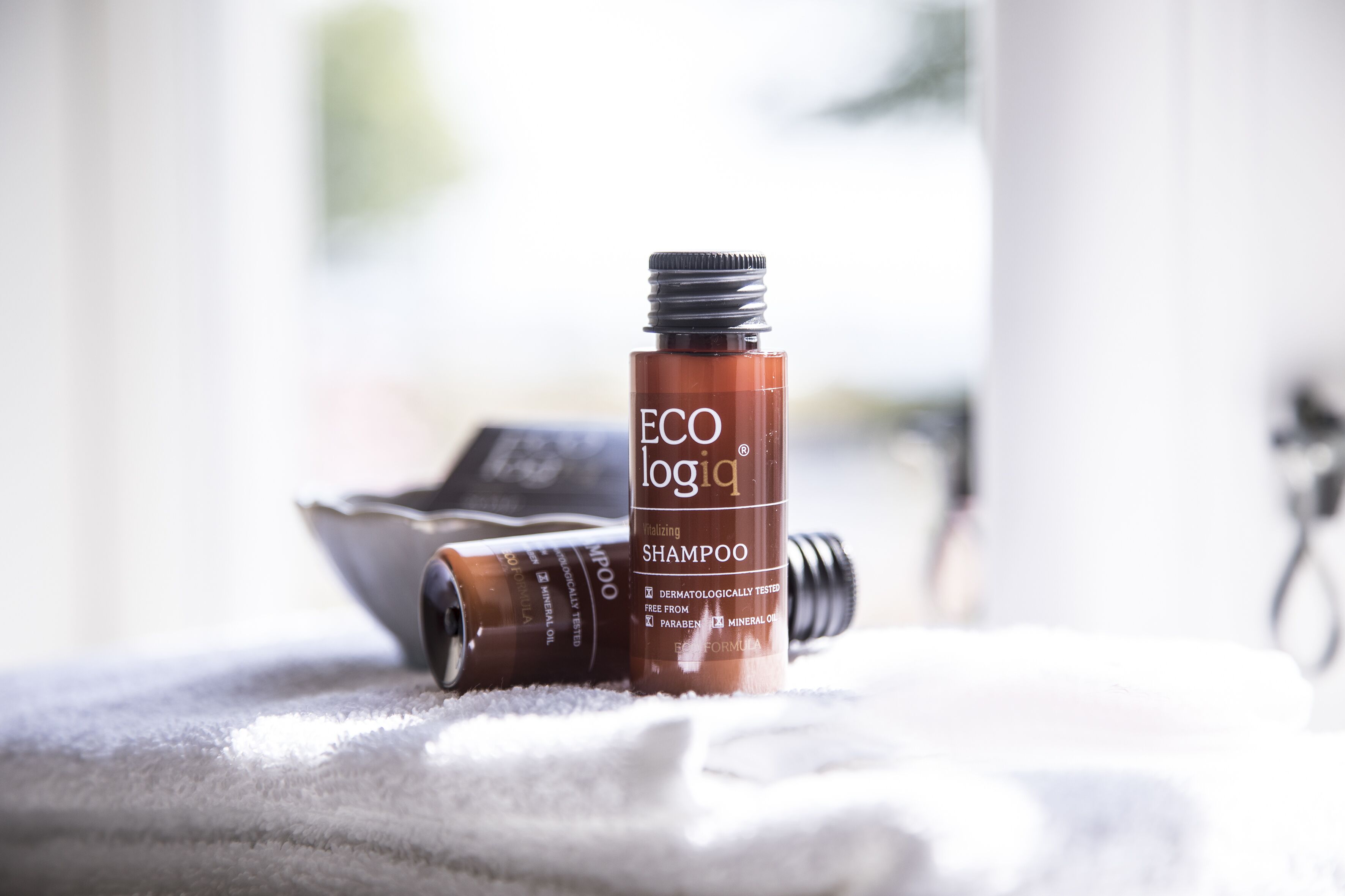 Une bouteille de shampoing ECOlogiq sur une serviette blanche.