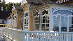 A building with a white picket fence, arched windows, and a yellow facade. - Ballebro Færgekro (Sønderborg)