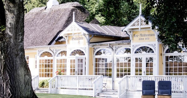 A traditional building with a thatched roof, white walls, and arched windows.