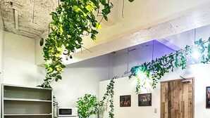 Uma sala de conferências com mesa de madeira, cadeiras pretas, quadro branco e plantas verdes.