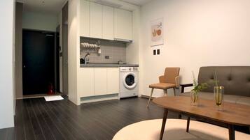A modern kitchen with built-in appliances, a dining area with a round table, and a sofa.